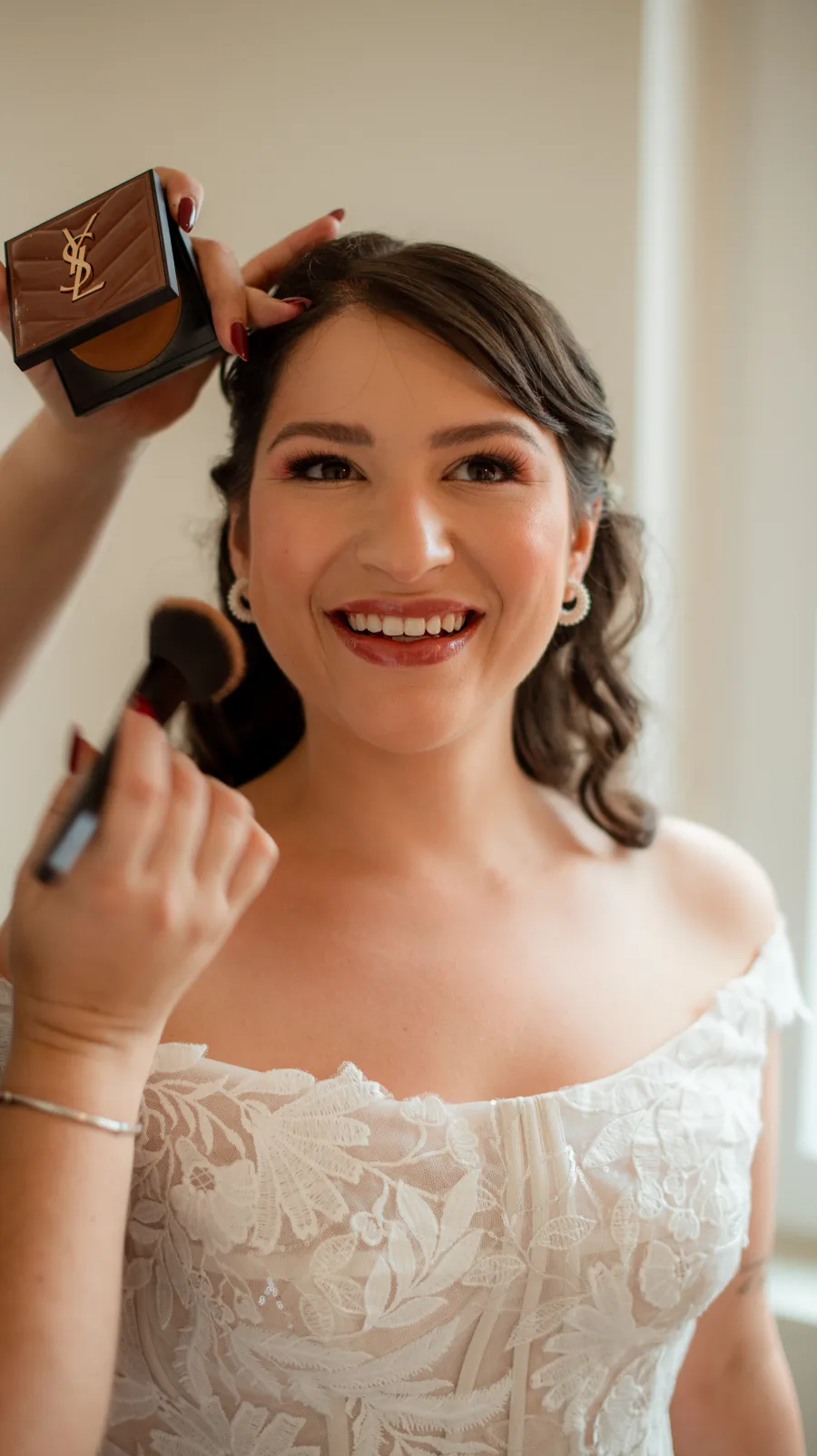 Noiva a sorrir em vestido de renda durante os preparativos, maquilhagem por Aline Alves